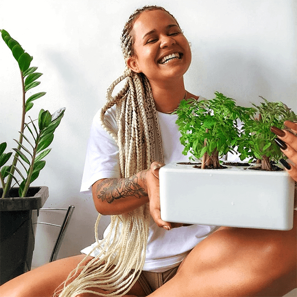 Mulher sorrindo segurando uma horta inteligente