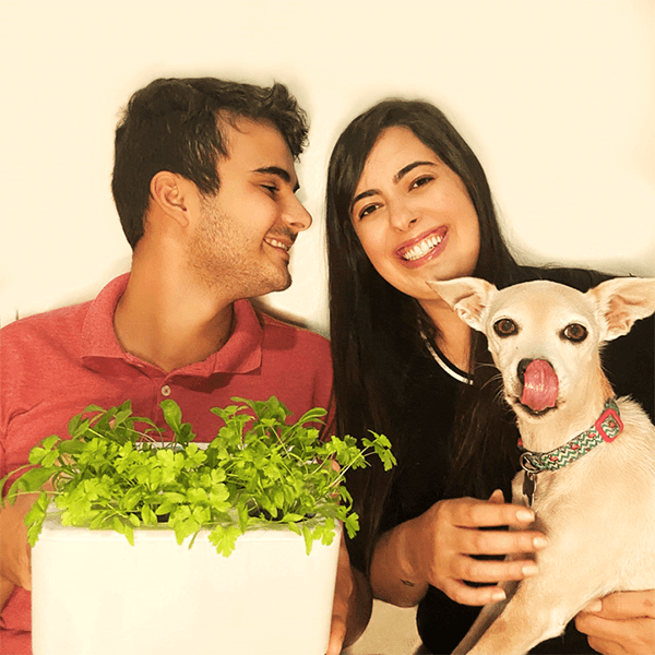 Casal feliz junto de seu cachorro, com uma horta inteligente crescida da Brota Company