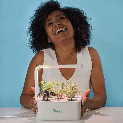 Mulher sorrindo com horta inteligente com luz artificial